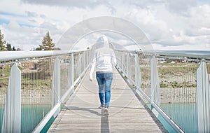 Back view of woman walking on Scott Pond Bridge, the bridge across Lake Tekapo in South island of New Zealand.