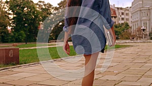 Back view woman walks to class holding book