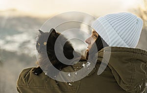 Back view of a Woman in white hat holding black cat outdoor