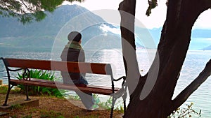 Back view of woman who is sitting by the sea on top of the cliff, Montenegro.