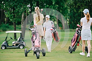 back view of women with golf gear walking on green lawn