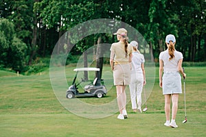 back view of women with golf gear walking on green lawn
