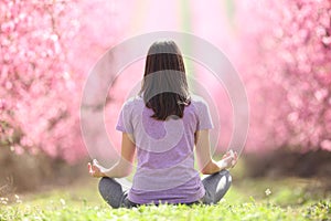 Back view of a yogi practicing yoga in a flowered field