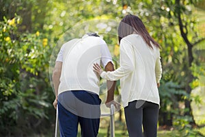 back view,a young adult daughter hand touching a senior father\'s back for support a father using a walker