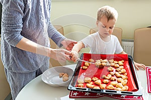 Back view young adult mother learn cooking sweet tasty cookies cute little toodler boy kid at home kitchen. Mom with