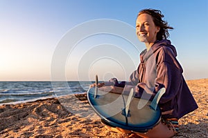 Back view young adult slim sporty female surfer girl with surfboard sitting on sand at ocean coast wave against warm