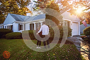 Back view of young American couple standing and looking at first home