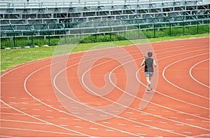 Back view of young athlete runner woman running in the running track in stadium.