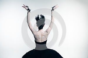 Back view of young ballerina wearing black tutu, stage dress posing  on white studio backgorund