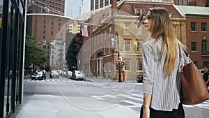 Back view of young beautiful businesswoman going to work in New York, USA and looking on window of office. Slow motion.