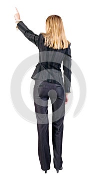 Back view of young blonde business woman pointing at wall .