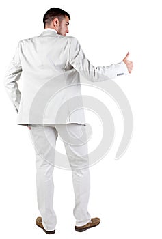 Back view of young business man in white suit going thumb up