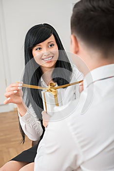 Back view of young businessman giving white gift