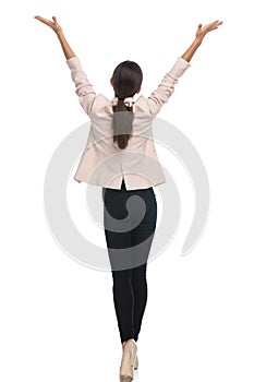 Back view of young businesswoman holding arms in the air