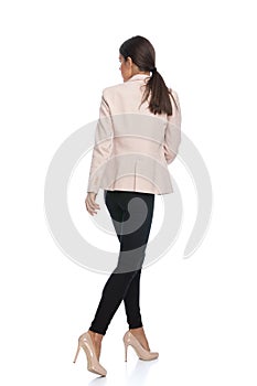 Back view of young businesswoman in pink jacket looking to side