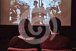 Back view of a young couple watching a retro movie in the cinema on a date