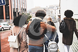 Back view of young diverse people group. Arm around