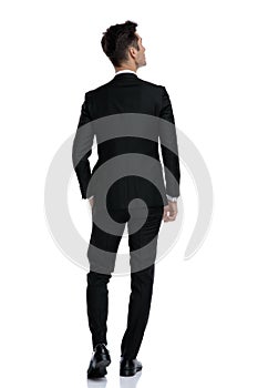 Back view of young elegant man in tuxedo looking up