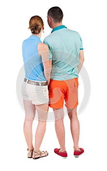 Back view of young embracing couple in shorts hug and look.