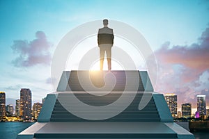 Back view of young european business man standing on top of stairs on bright city background with sky view. Leadership, growth and