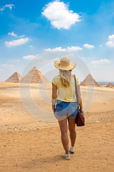 Back view of the young female with beautiful blond hairs. Back view portrait of a single woman watching the Great Pyramids of Giza