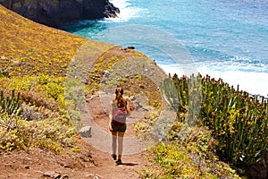 Back view young female hiker walking down to the sea on Macizo de Anaga in Tenerife photo