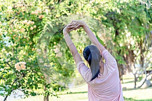 Back view of young fitness woman doing stretch exercise outdoors in park