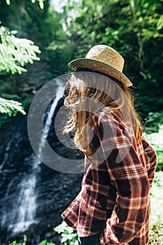 Back view of young girl from afar admires waterfall