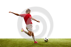 Back view. Young girl, football player in motion, playing on green grass, ready to hit ball isolated on white background