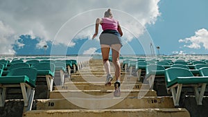 Back view of a young girl running upstairs at a stadium