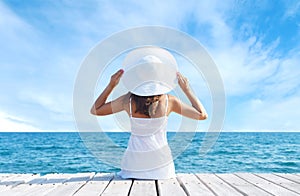 Back view of a young girl standing on a pier. Sea and sky background. Vacation and traveling concept.