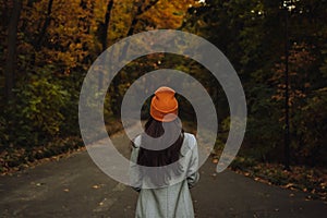 Back view of young girl walking alone on the street in autumn