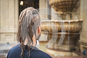 Back view of a young hipster man with dreadlocks and sidecut look at luxury restaurant