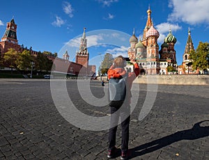 Back view of young hipster man using smartphone taking a picture in Saint Basil church at Moscow,Russia and blue sky background