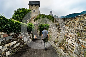Back view of a young male tourist with a backpack visiting Cochem Imperial castle in Germany
