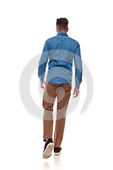Back view of young man in casual clothes walking