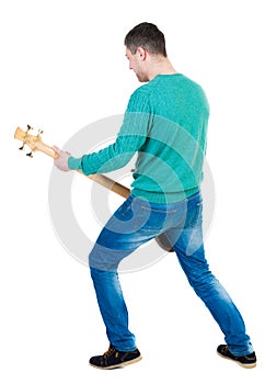 Back view of a young man with a guitar.