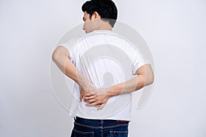 Back view of young man holding his back. He has back pain on a white background
