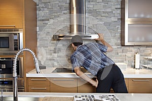 Back view of young man looking at chimney in model home kitchen