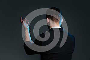 Back view of young man magician standing with raised hand