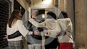 A drunk man with women in an alley leaving nightclub walk with arms around women