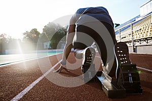 Back view of a young man in starting position for running