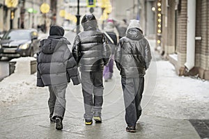 Back view of Young Men Walking in Urban Setting in winter. Modern city. Candid Street Photography
