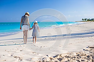 Back view of young mother and little daughter at caribbean beach