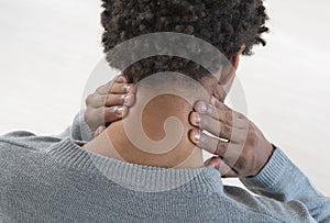 Back view of a young mulatto man with neck pain