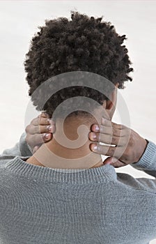 Back view of a young mulatto man with neck pain