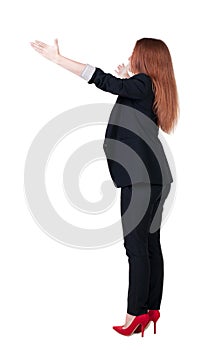 Back view of young redhead business woman pointing at wal