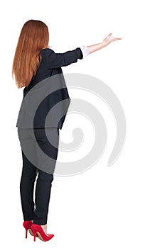 Back view of young redhead business woman pointing at wal