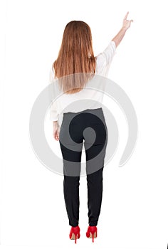 Back view of young redhead business woman pointing at wal