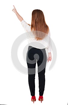 Back view of young redhead business woman pointing at wal